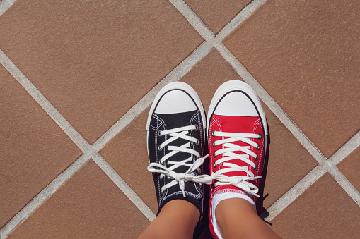 2-color sneakers, red and black. View from above pinning on girl