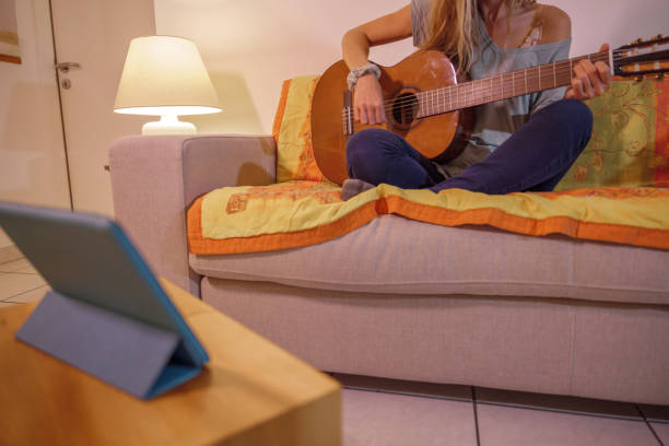 istock Woman learns guitar online from digital tablet 1330353054
