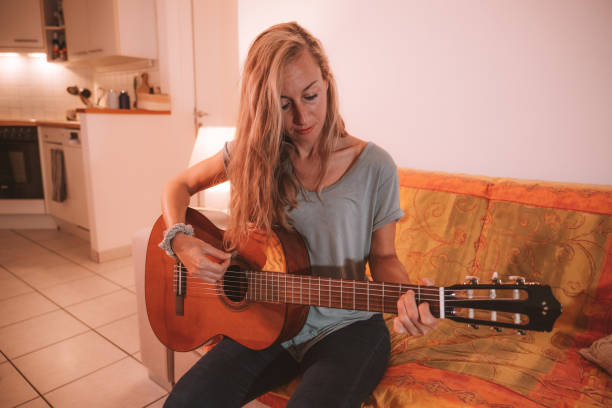 istock Woman plays guitar at home 1330353066