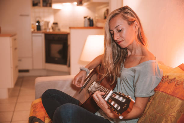 istock Woman plays guitar at home 1330353074