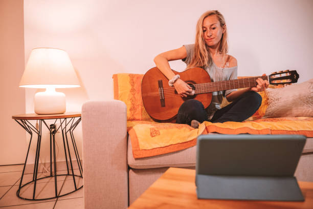 istock Woman learns guitar online from digital tablet 1330353082