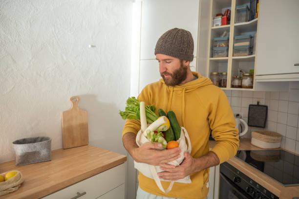 istock Man puts away vegetable groceries in the kitchen 1330353275