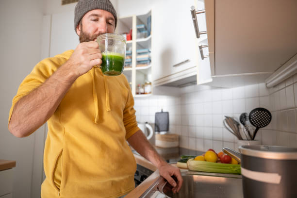 istock Man drinks freshly made green healthy smoothie in the kitchen 1330353278