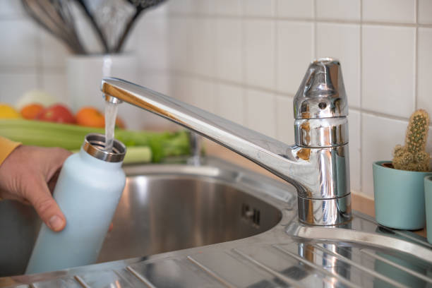 istock Man fills up reusable water bottle in the kitchen 1330353311