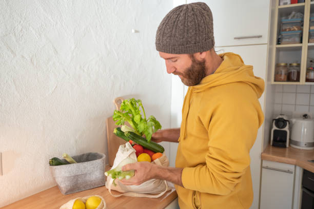 istock Man puts away vegetable groceries in the kitchen 1330353322