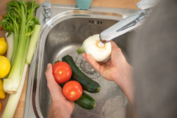 istock Man washes fresh vegetables in the kitchen 1330353333