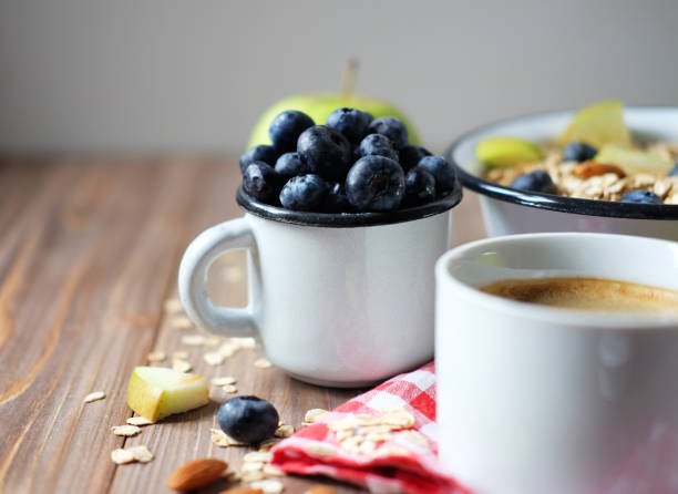 Oatmeal porridge, coffee, apple, berries and nuts on a wooden table