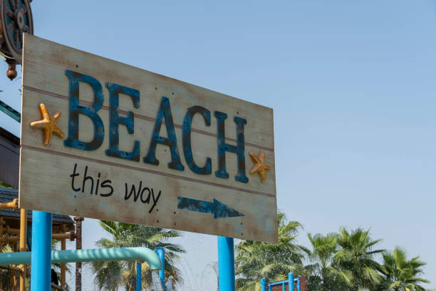 istock Tropical Beach this way directional sign with copy space on blue sky for vacation and summer concepts 1330354760