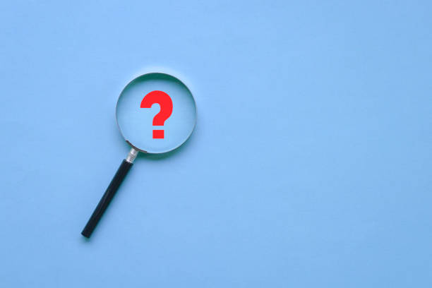 istock Magnifying glass and a red question mark on blue background. 1330357932