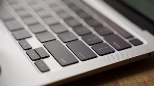 Closeup of finger pressing enter key on modern laptop keyboard. Man pushes enter button on notebook