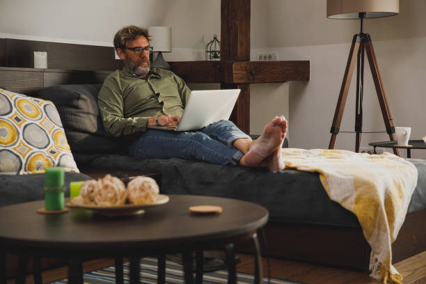 istock Mature man relaxing on the sofa and using laptop 1330359094