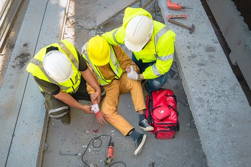 Trabajador de la construcción tiene un accidente en un sitio de construcción. Los ingenieros de la ayuda de emergencia proporcionan los primeros auxilios a los trabajadores de la construcción en accidentes. photo