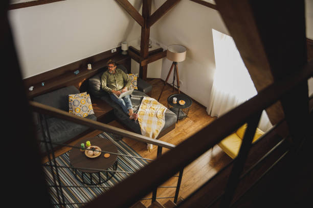 istock Wide shot of man relaxing on the sofa and catching up on some work, using laptop 1330360090