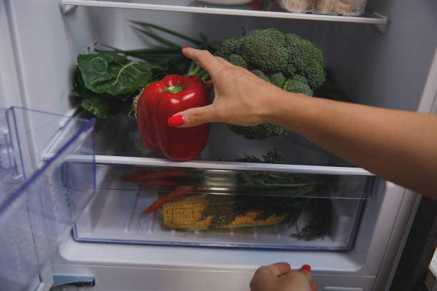 istock Woman putting a red bell pepper in the fridge 1330360097