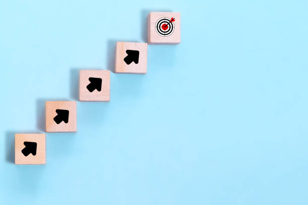 istock Wood block stacking as step stair on blue background virtual target board and arrow which print screen on wooden cube. Business achievement goal and objective target concept. 1330363772