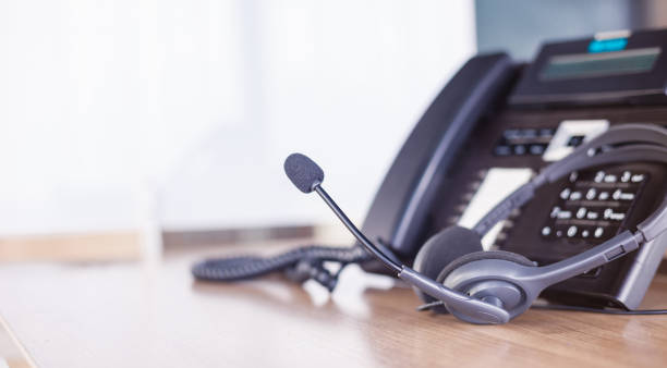 istock Communication support, call center and customer service help desk. VOIP headset on telephone keyboard. 1330368486