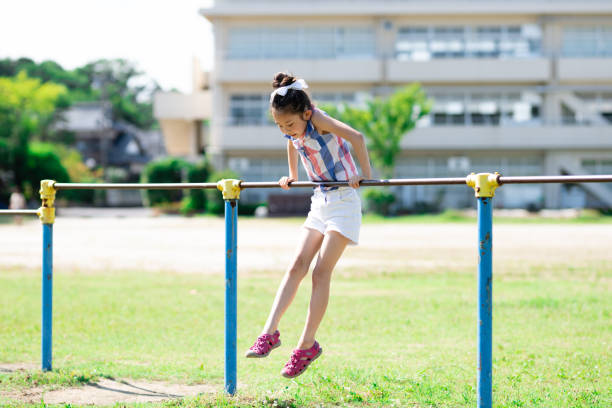 Girl playing horizontal bar in the schoolyard Girl playing horizontal bar in the schoolyard horizontal bar stock pictures, royalty-free photos & images