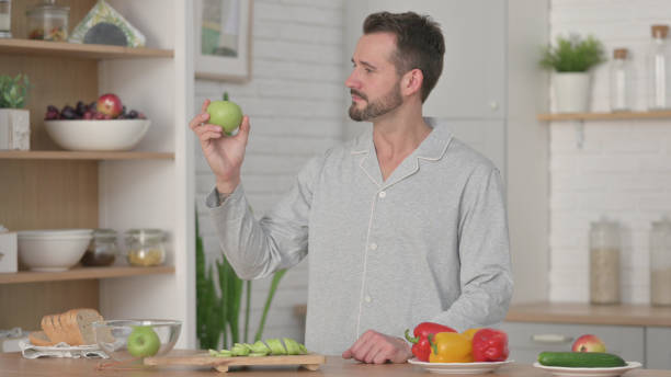 istock Healthy Young Man Holding Apple in Kitchen 1330374128