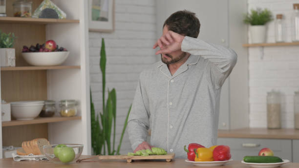 istock Healthy Young Man Cutting Cucumber in Kitchen 1330374131