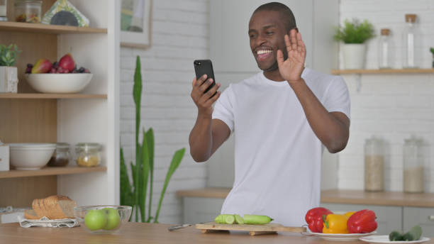 istock African Man Doing Video Call on Smartphone while Standing  in Kitchen 1330374136