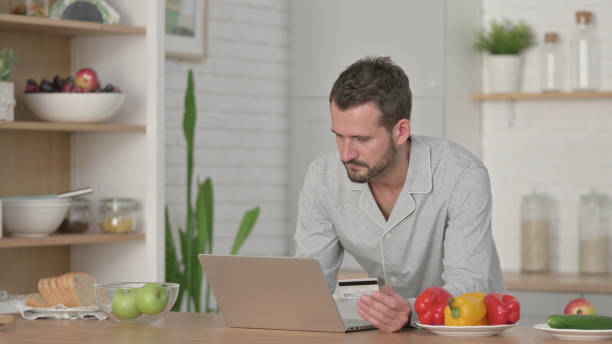 homme faisant des achats en ligne sur ordinateur portable dans la cuisine - 30061 photos et images de collection