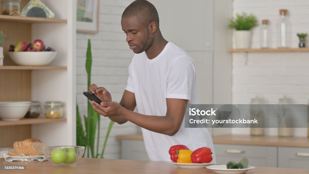 African Man Taking Picture of Fruits on Smartphone in Kitchen 20-29 Years Stock Photo