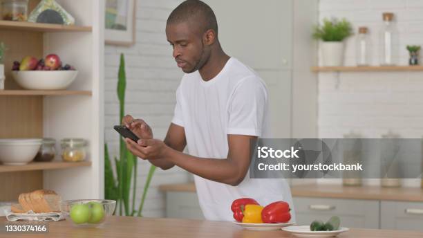 African Man Taking Picture Of Fruits On Smartphone In Kitchen Stock Photo - Download Image Now