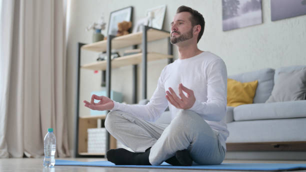 istock Young Man Meditating on Yoga Mat at Home 1330374180