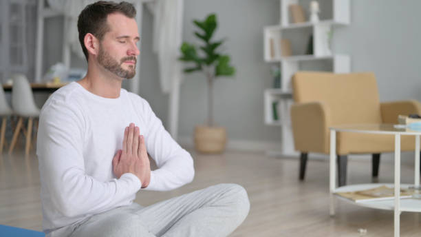 istock Young Man Meditating on Yoga Mat at Home 1330374837