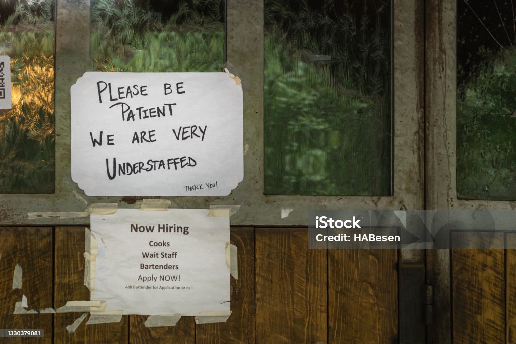 Understaff hiring sign Rustic sign in restaurant window during time of Covid stating restaurant is understaffed and is hiring in a struggling economy, showing the plight of small businesses in the post-pandemic economy. Help Wanted Sign Stock Photo