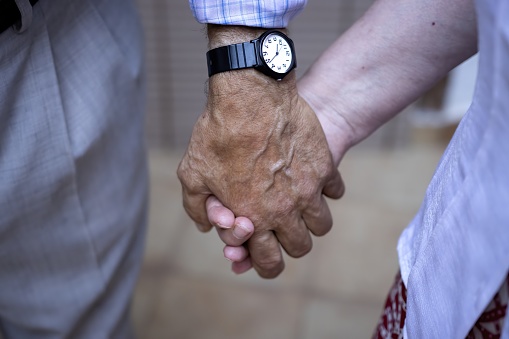 lderly couple holding hands, You and me forever. Close-up of elderly couple holding hands indoors, he is wearing a wristwatch