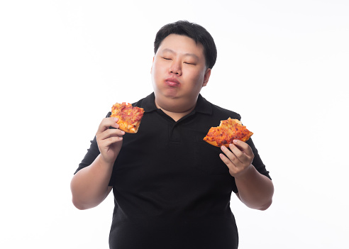 Young Funny Fat Asian man eating hawaiian and cheese pizza isolated on white background, Unhealthy concept.