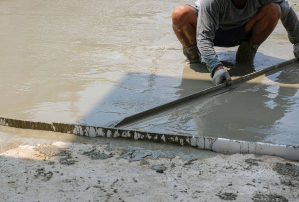 istock worker man working wet cement  on floor by use trowel with two hands spreading poured smooth concrete for strong street after dry. 1330381805