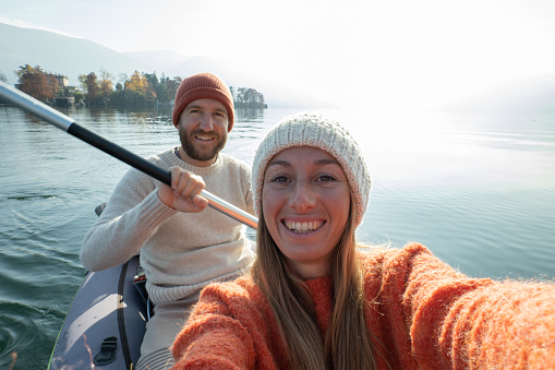 Young couple canoeing take selfie on beautiful mountain lake in Switzerland. 
Inflatable canoe on water with mountain scenery
People travel outdoor activity concept