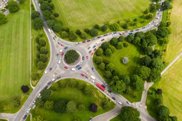 Aerial view of a busy countryside road roundabout at rush hour with traffic queueing