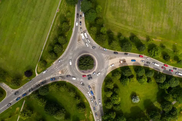 Aerial view of a busy countryside road roundabout at rush hour with traffic queueing