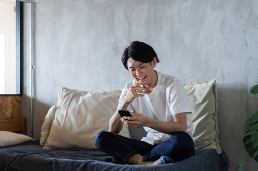 Young man using smartphone at home alone