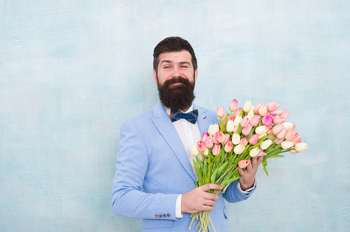 Spring vibes. Man bearded suit bow tie hold tulip flowers bouquet. Gentleman romantic surprise for her. Flowers delivery. Gentleman romantic date. Birthday greetings. Best flowers for girlfriend.