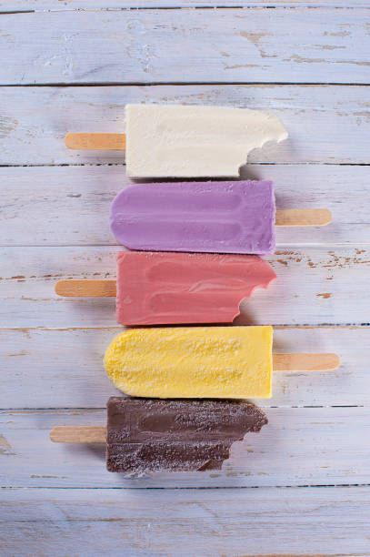 Several different flavored popsicles together, some bitten. Top view