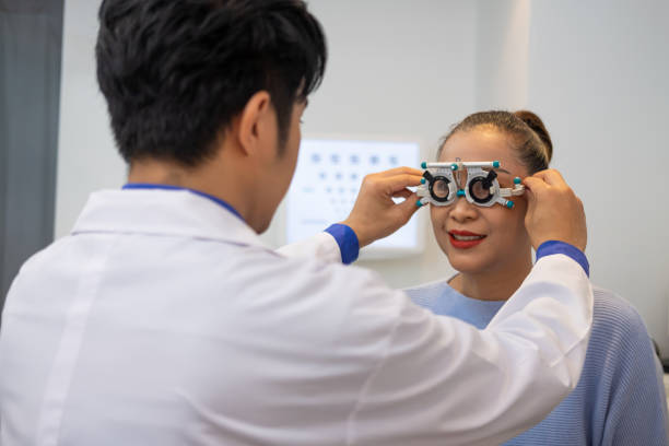 selektywne skupienie na twarzy optometrysty. podczas gdy lekarz za pomocą penlight i subiektywne załamanie do zbadania systemu wzrokowego oczu starszych pacjentek z profesjonalną maszyną przed wykonane okulary. - penlight zdjęcia i obrazy z banku zdjęć