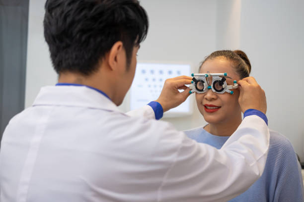 selective focus at optometrist face. while doctor using penlight and subjective refraction to  examine eye visual system of elder patient women with professional machine before made glasses. - penlight imagens e fotografias de stock