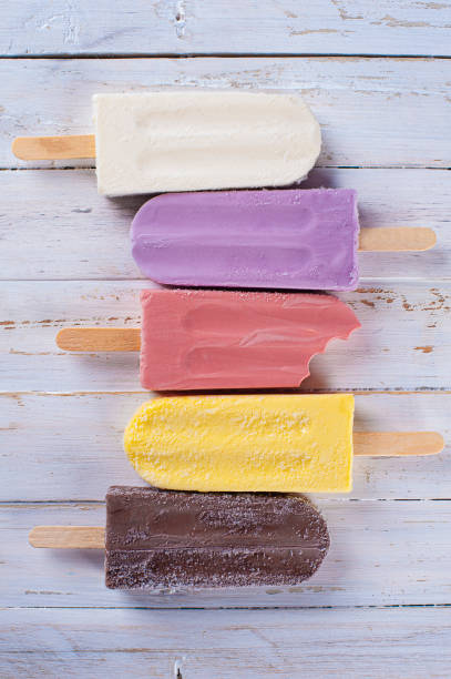 Several different flavored popsicles together, some bitten. Top view