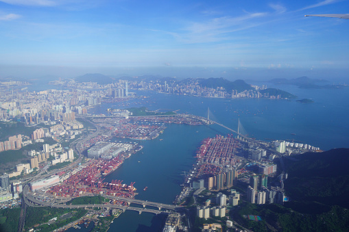 Airplane flies over Hong Kong. Passenger jet plane flying above urban scene. Hongkong flight. Asian destination