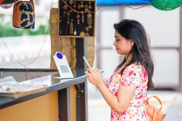 Young female Customer using digital payment method, scanning QR code with smartphone at a retail store to send money as payment using credit or Debit card. Young female Customer using digital payment method, scanning QR code with smartphone at a retail store to send money as payment using credit or Debit card- concept of digital or contact less payment, e-transfer, technology and lifestyle. coding qr code mobile phone telephone stock pictures, royalty-free photos & images