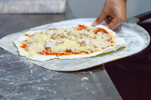 process of preparation of a delicious pizza by an unrecognizable chef in a restaurant - pizza sauces chef making imagens e fotografias de stock