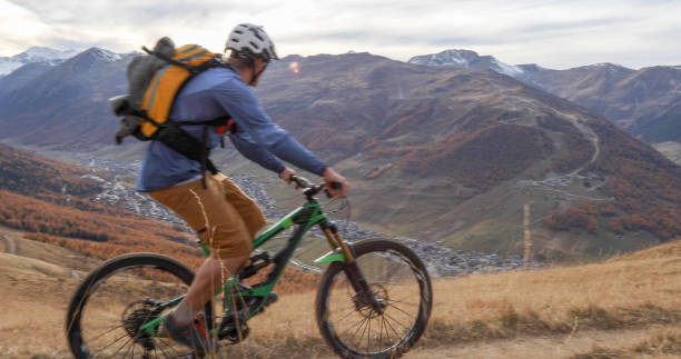 istock Mountain biker rides along grassy mountain ridge 1330399303