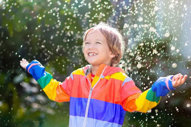 Photo of Child playing in autumn rain. Kid with umbrella.