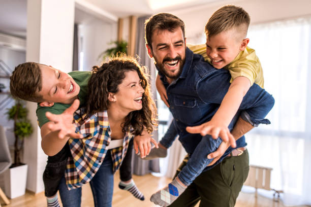 Playful family having fun at home. Playful two parents carrying their two boys in the living room of their home. They love their new home. mum new boyfriend stock pictures, royalty-free photos & images
