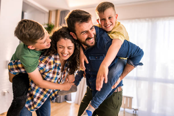 Playful family having fun at home. Playful two parents playing with their two boys and laughing. mum new boyfriend stock pictures, royalty-free photos & images