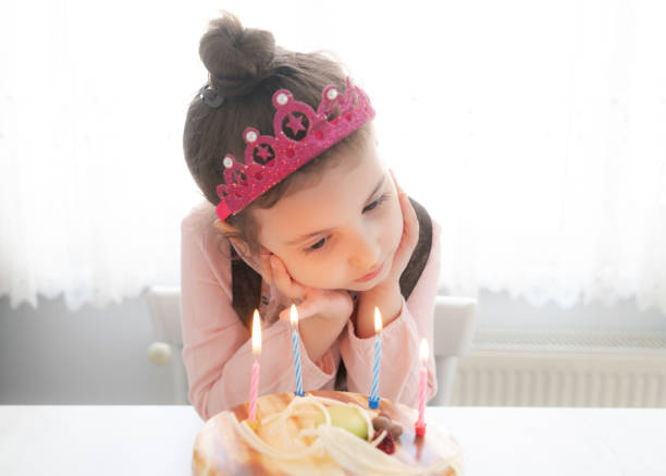 Happy girl making wish while blowing candles